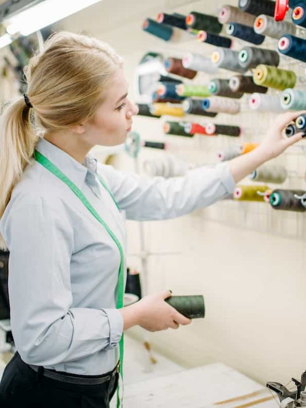 Clothes designer chooses color threads, manufacture on sewing factory. Seamstress, dressmaking or tailoring