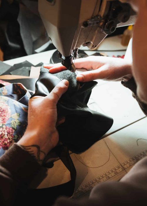 Cropped photo of young man shoemaker at footwear workshop.